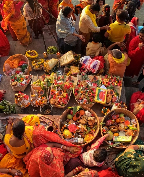 Devotees offering prayers and arghya to Sun God during Chhath Puja celebrations, at a riverbank or pond.